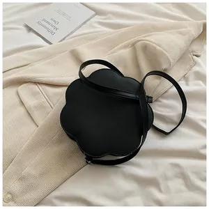Détail du sac à bandoulière noir en forme de fleur sur un tissu texturé en velours
