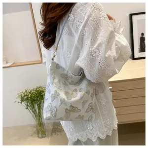 Detailed butterfly embroidery on bucket bag with blue and gold patterns on white leather