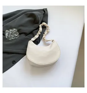 Detail view of a white crescent shoulder bag featuring a unique pleated ruched strap design