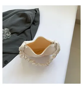 Detail view of the pleated handle and beige fabric lining of this off-white shoulder bag