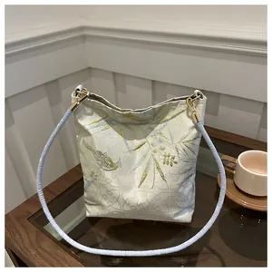 Detail of embroidered satin bucket bag with floral patterns and light blue strap