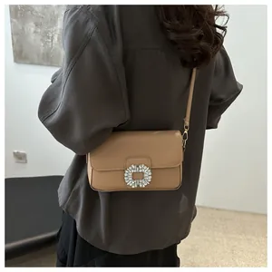 Model wearing a tan litchi pattern crossbody bag with a sparkling crystal square buckle