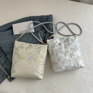 Chic embroidered bucket bags featuring floral and butterfly patterns with woven straps