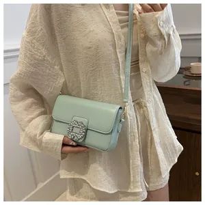 Close-up of a mint green crossbody bag featuring a crystal-encrusted square buckle detail
