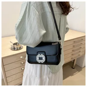 Detail of a black square crossbody bag featuring a sparkling crystal rhinestone buckle