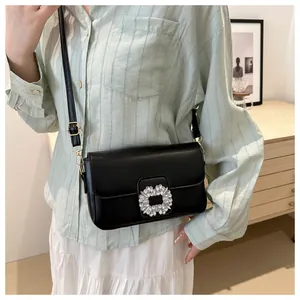 Close-up of black leather crossbody bag with shiny square diamond buckle and gold hardware