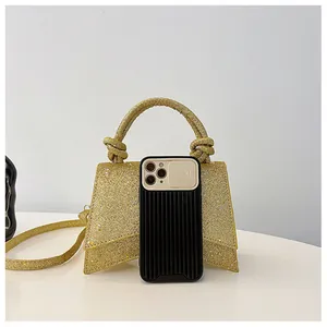 Mini sac à main pailleté doré avec base incurvée et poignée nouée sur fond moderne