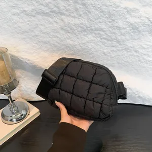 Borsa a tracolla in nylon trapuntato nero con ampia tracolla in un ambiente moderno