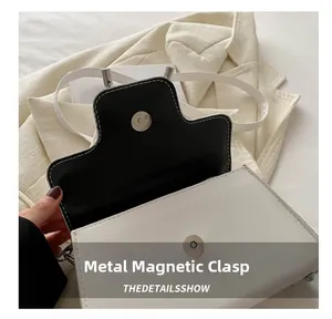 Detail einer weißen Handtasche aus Leder mit Magnetverschluss und schwarzem Innenfutter