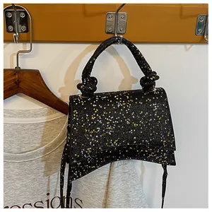 Détail du sac sablier à paillettes noires avec base incurvée et poignée à nœuds