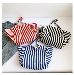 Three colorful striped canvas tote bags in red, black, and blue with a denim jacket prop