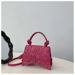 Vue détaillée du sac à main fuchsia à paillettes avec poignée nouée et bandoulière fine