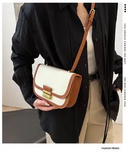 Detail of canvas and brown leather stitching saddle bag with gold metal clasp