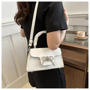 Detailaufnahme einer weißen Handtasche mit glitzernder Strassschleife und Silberbeschlag