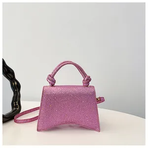 Détail d'un sac à main rose pailleté avec poignée nouée et base incurvée unique
