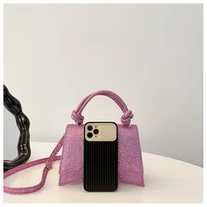 Mini sac à main rose pailleté avec poignée nouée et bandoulière montré avec un téléphone