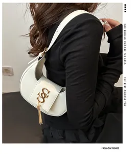 Détail du sac en croissant ivoire avec logo S doré et pendentif à pompon élégant