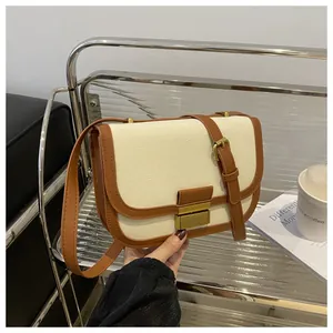 Detail of minimalist saddle bag showing beige canvas and brown leather contrast stitching