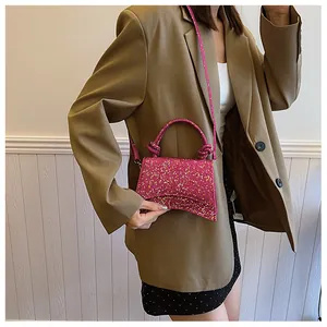 Détail d'un sac à main fuchsia pailleté avec base incurvée et poignée à nœud décoratif