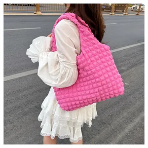 Détail du sac à bandoulière rose fuchsia à texture bulle avec robe en dentelle