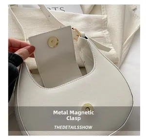 Détail du sac croissant blanc avec boucle magnétique dorée et cuir texturé élégant