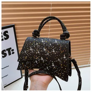 Détail du sac à main noir pailleté avec sequins étoiles et poignée supérieure à nœuds