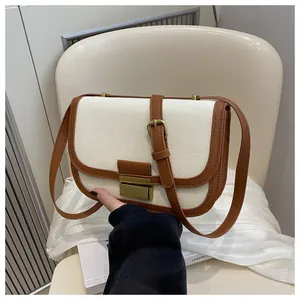 Detail of vintage saddle bag featuring white canvas texture and brown leather trim accents