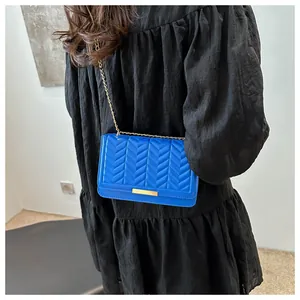 Detail of bright blue quilted leather crossbody bag with elegant gold chain and metal clasp