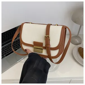 Close-up of contrast color saddle bag featuring vintage metal push-lock and leather trim