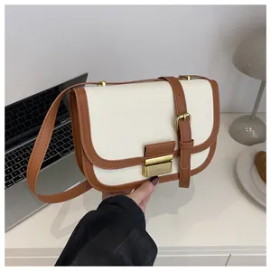 Detail of contrast stitch saddle bag featuring beige canvas and brown leather strap texture