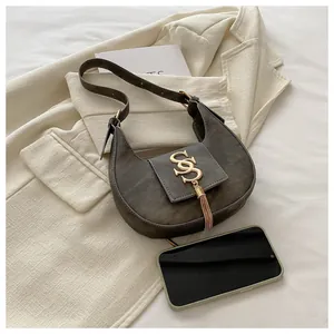 Détail du sac croissant gris montrant le logo SS doré, le gland et le fini mat