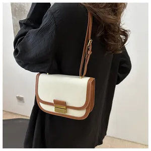 Detail of canvas shoulder bag with brown leather trim and golden metal clasp