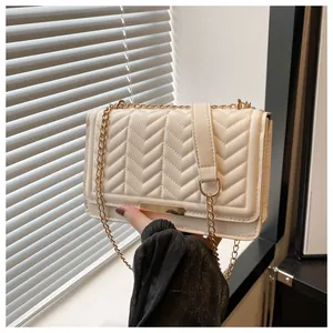 Detail of cream quilted crossbody bag with chevron stitching and golden chain strap