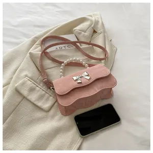 Detail of light pink pleated leather bag featuring a pearl handle and silver bow buckle