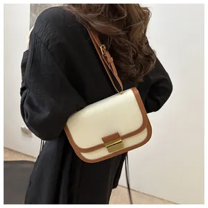 Detail of canvas and brown leather crossbody bag showing the golden metal lock