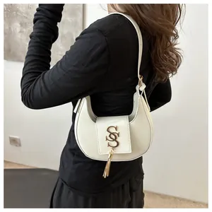 Vue détaillée du sac à bandoulière blanc en croissant avec logo doré et pompon