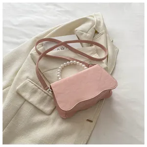 Detail of pink fashion handbag with pearl handle and wavy base on cream blazer
