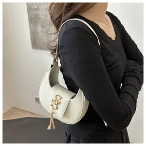 Détail du sac hobo avec logo doré entrelacé et pendentif à pompon métallique