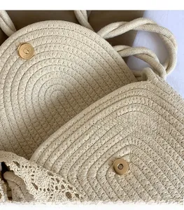 Detail of a polished metal magnetic buckle on a cream woven bag with lace trim