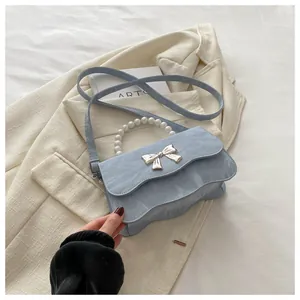 Close-up of light blue marble texture handbag with pearl handle and silver bow