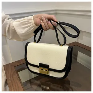 Detail of color-block saddle bag with canvas texture, black leather trim and gold buckle