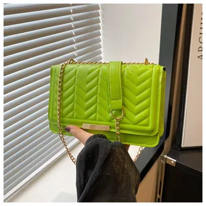 Detail of neon green crossbody bag with V-quilted stitching and gold chain strap