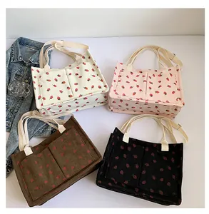 Detail view of corduroy tote bags with red strawberry print in four various colors