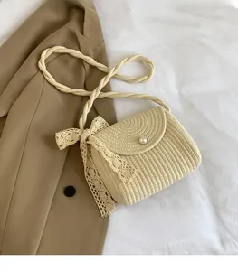 Detail of beige woven straw shoulder bag with pearl clasp and lace bow decoration