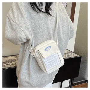 Detailed view of the white canvas crossbody bag with clear mesh pocket and fashion patch