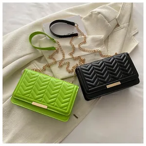Detail of neon green and black chain crossbody bags with elegant V-shaped quilting finish