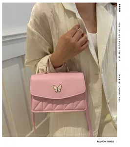 Close-up of pink quilted crossbody bag with decorative metal butterfly buckle and leather texture