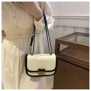 Detail shot of canvas and black leather crossbody saddle bag with golden clasp on model