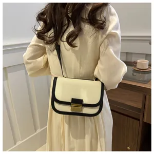 Detail of contrast stitch saddle bag with gold lock and black leather trim accents