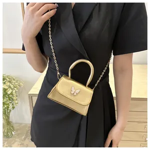 Détail de mini sac doré avec ornement papillon et bandoulière en chaîne élégante